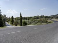 a scenic view of a street in a rural area with trees and hills in the background