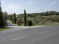 a scenic view of a street in a rural area with trees and hills in the background