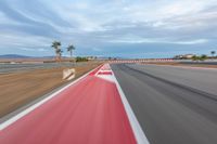 a photo of a dirt race track with sun setting in the distance of the track