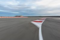 a photo of a dirt race track with sun setting in the distance of the track