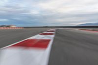 a photo of a dirt race track with sun setting in the distance of the track