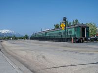 a train that is on a rail road track near some mountains or snow covered peaks