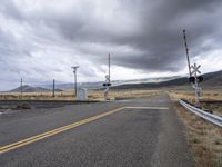 a road with two railroad signals on each side of it, and a telephone tower standing near by