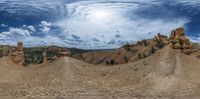 there is a panorama of a desert and sky with clouds and some rocks in the background