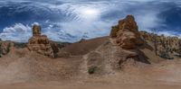 three large rocks with one sticking out in the distance, with a person riding a bike on the bottom of it