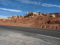 a long road with white lines leading towards the mountains of rocks and rock formations in the desert