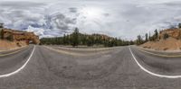 a wide angle panoramic shot of a winding road in front of a canyon