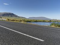 this is an image of a road with water and grass on both sides of the road