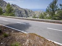 the road is paved with white lines down to the edge of the valley and ocean behind
