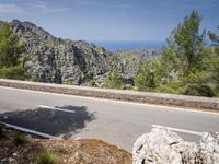 the road is paved with white lines down to the edge of the valley and ocean behind
