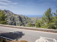 the road is paved with white lines down to the edge of the valley and ocean behind