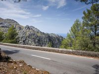 the road is paved with white lines down to the edge of the valley and ocean behind