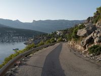 a road going up into a cliff area with a boat coming out onto the water