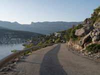 a road going up into a cliff area with a boat coming out onto the water