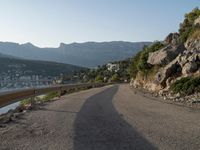 a road going up into a cliff area with a boat coming out onto the water