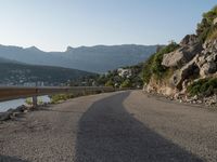 a road going up into a cliff area with a boat coming out onto the water