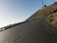 a black paved roadway is between hills and tall mastons on top of a hill