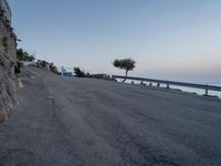 a road that has some buildings next to the sea and rocks on both sides of it