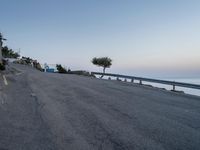 a road that has some buildings next to the sea and rocks on both sides of it