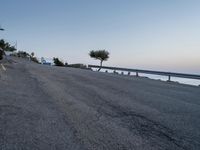 a road that has some buildings next to the sea and rocks on both sides of it