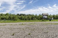 the large field is filled with stones and dirt with trees on the side and clouds in the sky