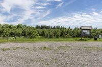 the large field is filled with stones and dirt with trees on the side and clouds in the sky