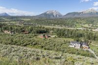 a rural setting with buildings, green trees and mountains in the background of blue skies