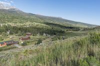 a rural setting with buildings, green trees and mountains in the background of blue skies