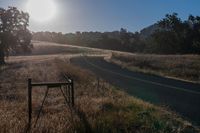 there is a road that goes along the side of a hill in front of the sun