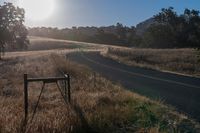 there is a road that goes along the side of a hill in front of the sun