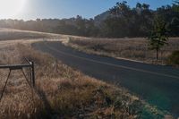 there is a road that goes along the side of a hill in front of the sun