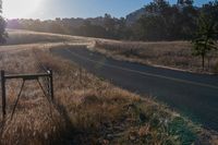 there is a road that goes along the side of a hill in front of the sun