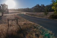 there is a road that goes along the side of a hill in front of the sun