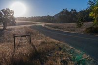 there is a road that goes along the side of a hill in front of the sun