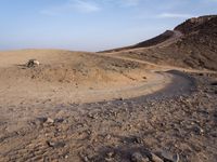 a truck on a dirt road in the desert with rocks and stones on the ground