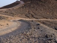 a truck on a dirt road in the desert with rocks and stones on the ground