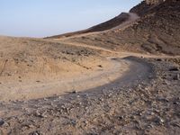 a truck on a dirt road in the desert with rocks and stones on the ground