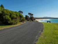 empty roadway by the beach with green grass and trees near by on hill at top