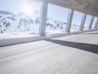 a long snowy highway with lots of snow on the side of it and snow capped mountains in the distance