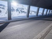 a long snowy highway with lots of snow on the side of it and snow capped mountains in the distance