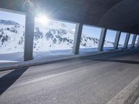 a long snowy highway with lots of snow on the side of it and snow capped mountains in the distance