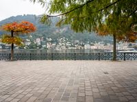 a stone patio by the water overlooking a city and a lake with many small buildings and trees
