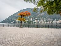 a stone patio by the water overlooking a city and a lake with many small buildings and trees