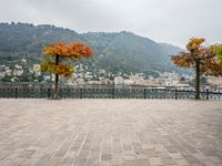 a stone patio by the water overlooking a city and a lake with many small buildings and trees