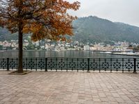 a stone patio by the water overlooking a city and a lake with many small buildings and trees