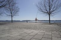 a street with trees and a boat ramp on the side of it near the water