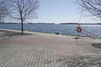 a street with trees and a boat ramp on the side of it near the water