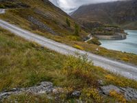 a view looking down at a winding trail with a lake in the background on a cloudy day