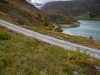 a view looking down at a winding trail with a lake in the background on a cloudy day