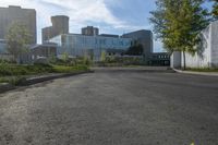 a city street surrounded by grass and tall buildings at the end of a street there is a paved pathway in front of the building